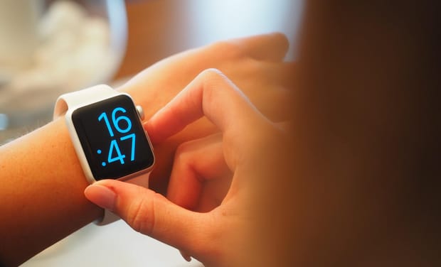 Close-up photo of a smartwatch displaying the time 16:47 on a slender woman's wrist.